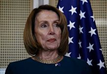 Pelosi Tracker Ignites Wall Street Frenzy Person standing near American flag indoors