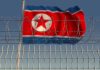 North Korea Hacks U.S. Paychecks—Nobody Stopped It Barbed wire fence with North Korean flag behind.