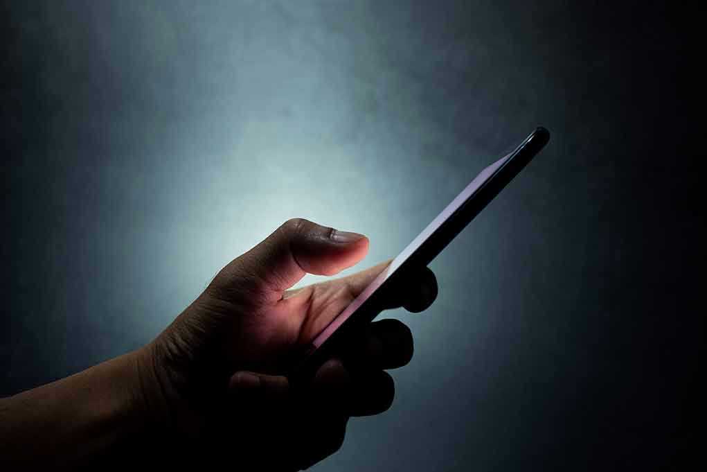 Hand holding a smartphone in the dark.