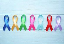 Cancer Explosion Hits Young Americans – No One Warned Them Colorful awareness ribbons on light wooden background.