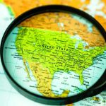 Gen Z Uprising Shakes Mexico City Magnifying glass over United States on map.