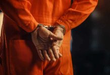 Kristi Noem CATCHES 150 Sex Offenders Person in orange jumpsuit with handcuffs behind back.
