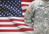 UNPRECEDENTED Military Rebellion Video Goes Viral Soldier in camouflage uniform standing before American flag.