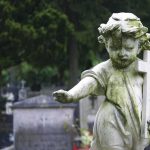 Blair Witch Comes Alive: Dudleytown’s Creepy Reality Weathered statue of a child angel holding a cross in a cemetery