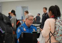 TSA Procedures Questioned After Pregnant Woman Encounter TSA agent checks passengers documents at airport security.