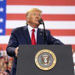 Trump’s Bold Move: Ukraine’s Future in Peril? Man speaks at podium with U.S. flag background.