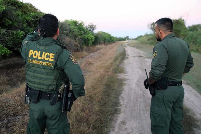 2079342073 Two U.S. Border Patrol officers observing a dirt path.