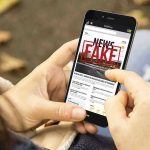 White House Targets ‘Fake News’ – Media in Chaos Person holding smartphone displaying fake news notification.
