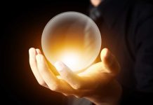 Apocalyptic 2026 Predictions Are Gaining Traction A hand holding a glowing crystal ball against a dark background