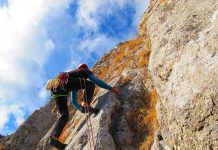 Cliff Jump Gone Wrong Leaves Him SHATTERED A climber ascending a rocky cliff under a blue sky