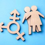 Sex Definition War Hits Schools Again Wooden transgender symbol and couple figures on blue background.