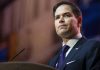 Rubio DESTROYS Senator — Cartel War Explodes Man in suit speaking at podium.
