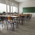 10% Top US Schools From This State Empty classroom with desks, chairs, windows, and chalkboard.
