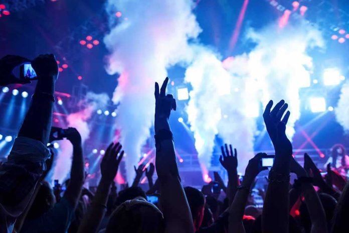 shutterstock_122464855.jpg Crowd at a concert with hands raised and smoke effects in the background