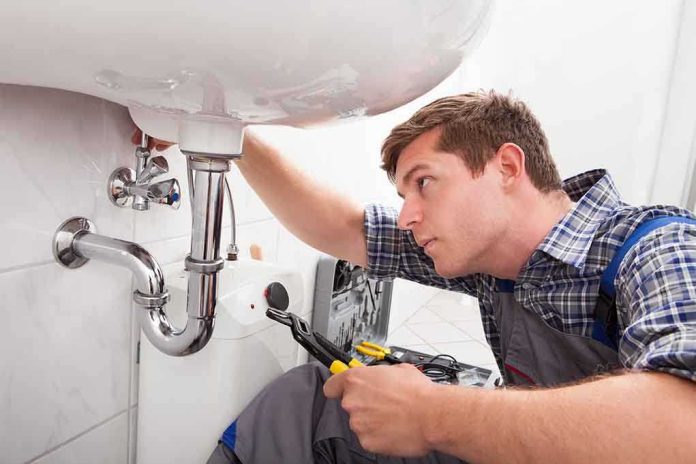 A plumber working under a sink with tools