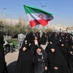 BRUTAL Regime Slaughters Thousands Group of women in black attire marching with an Iranian flag