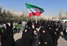 Iran SLAUGHTERS Protesters Group of women in black attire marching with an Iranian flag