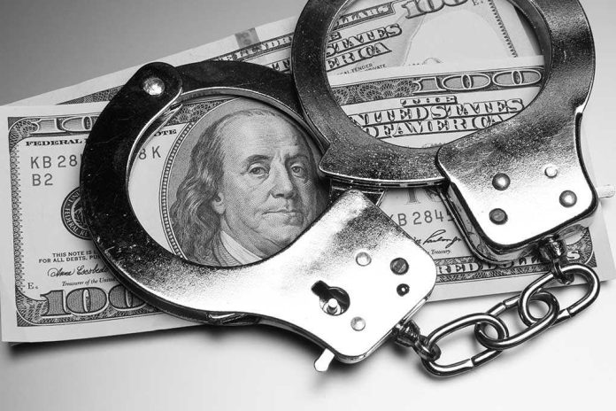 Handcuffs placed over a stack of hundred dollar bills