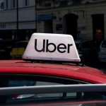 Uber Jury Crushes Contractor Shield Uber sign on top of a red car in an urban setting