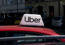 Uber Jury Crushes Contractor Shield Uber sign on top of a red car in an urban setting