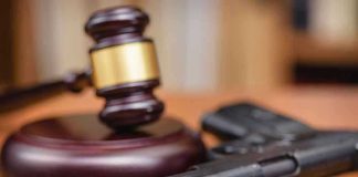 Biden Released Him, Now A Woman is Dead Gavel and handgun on a wooden surface.