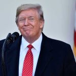 Jon Stewart Praises Trump—Wait, What? Man in suit and tie speaking at podium.