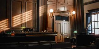 Judge Forces Prison Photo PURGE Empty courtroom with judges bench and wooden decor.
