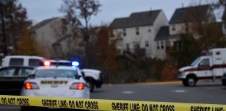 Teen and Accomplice Charged in Triple Family Murder Sheriff line tape blocking scene with police and ambulance.