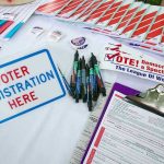Supreme Court Chaos: Race Map Overturned! Voter registration table with forms, pens, and brochures.