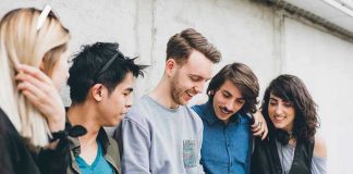 Harvard Flags Alarming Drop In Teen Hangouts Group of friends looking at a smartphone.