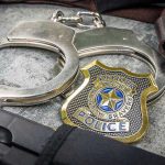 $40M Gold Stash: Top CIA Official ARRESTED Handcuffs, officer badge, and firearm on textured surface.