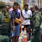 Six Bodies Found: Chilling Border Tragedy Border patrol agents inspecting group of individuals in line.