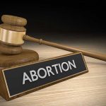 Court OVERRULES FDA on Abortion Pill Safety Gavel and sign reading Abortion on a wooden surface.