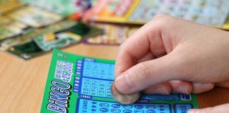 Lottery WIN—Generosity Pays $586K Reward! A person scratching off a bingo lottery ticket with a coin