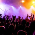Springsteen SNUBS Christie – On Purpose? Crowd at a concert with raised hands and colorful stage lights