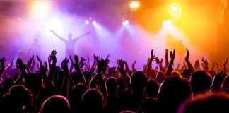 Springsteen SNUBS Christie – On Purpose? Crowd at a concert with raised hands and colorful stage lights