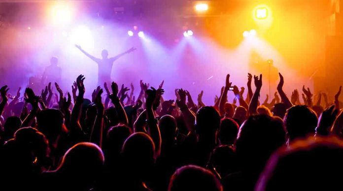 shutterstock_214402048 Crowd at a concert with raised hands and colorful stage lights
