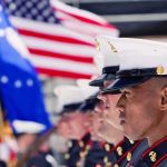 Pentagon Reenlists Marine Hero Marines in uniform standing in formation with flags in the background