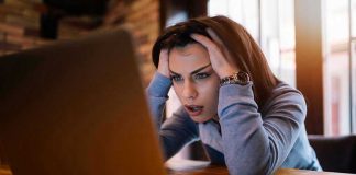 Mystery Codes Flood Inboxes — What’s Microsoft Hiding? Woman frustrated at laptop, holding her head.