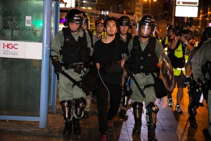 Police arresting a person during a nighttime protest