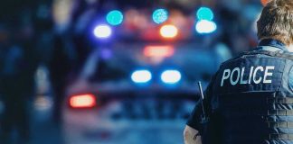 Pre-Dawn MASS SHOOTING — MANHUNT Launched! Police officer with patrol car and flashing lights.