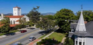Justice TWIST Shuts Church Case Street with church, parked cars, and trees.