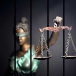Top Judge ARRESTED — Loses CONTROL! Blindfolded Lady Justice statue holding scales behind bars.
