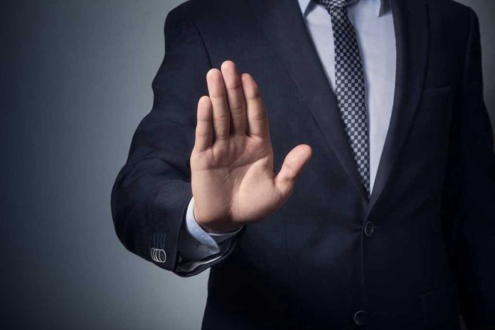 611111144-1 Man in suit with hand raised, signaling stop.