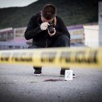 Barnyard Horror SHOCKS Vegas Show Crime scene photographer behind police tape with evidence marker.
