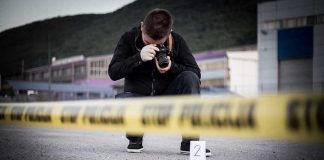Barnyard Horror SHOCKS Vegas Show Crime scene photographer behind police tape with evidence marker.