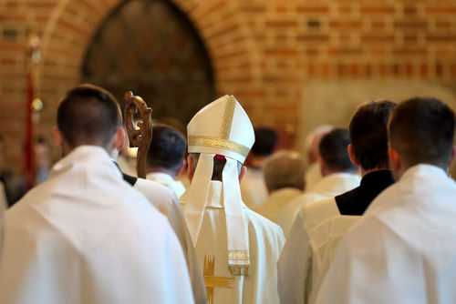 Clerics in white robes facing altar in church