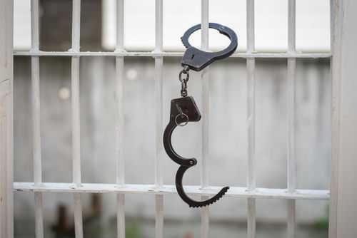escape680970664 Open handcuff hanging on jail bars