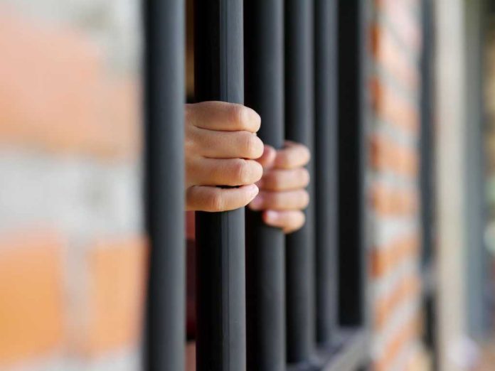 Hands gripping prison bars