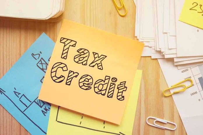 shutterstock_1722119749-1- Sticky note labeled Tax Credit on a desk with papers and charts